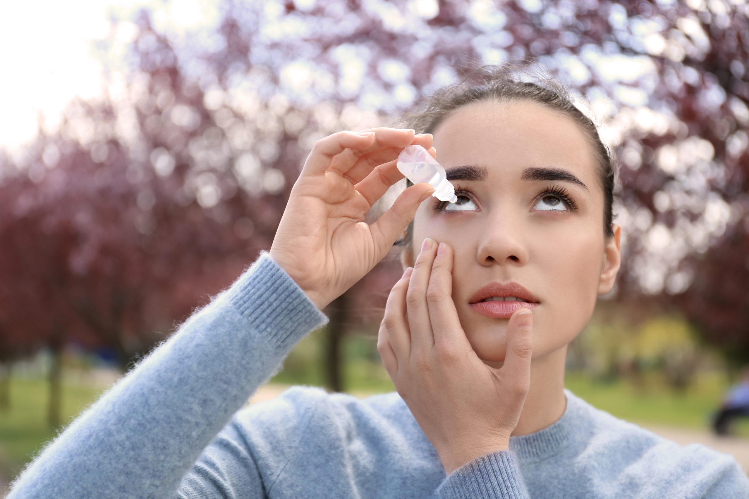 women putting eye drops in her eye