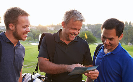 3 Golfers looking at a score card