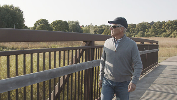 Older man walking outside with UV-blocking glasses